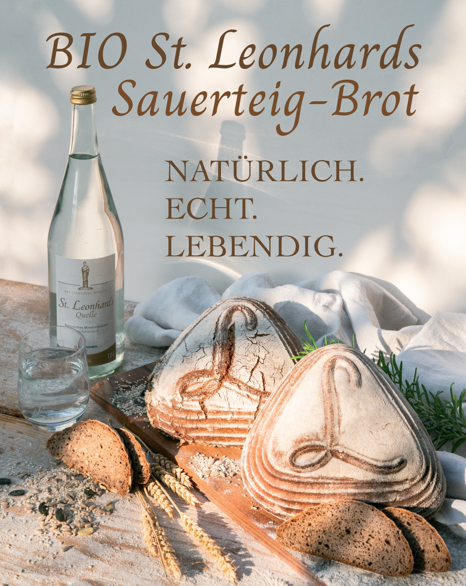 Plakat mit zwei BIO St. Leonhards Sauerteig-Brote. Natprlich. Echt. Lebendig. Und im Hintergrund eine Wasserflasche der St. Leonhards Quelle